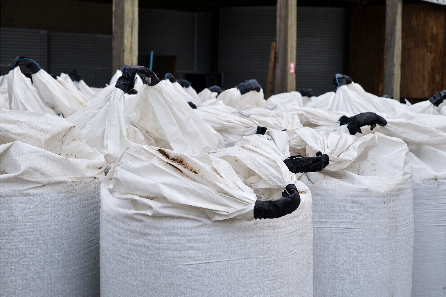 Des big bags de grain alignés sous un hangar