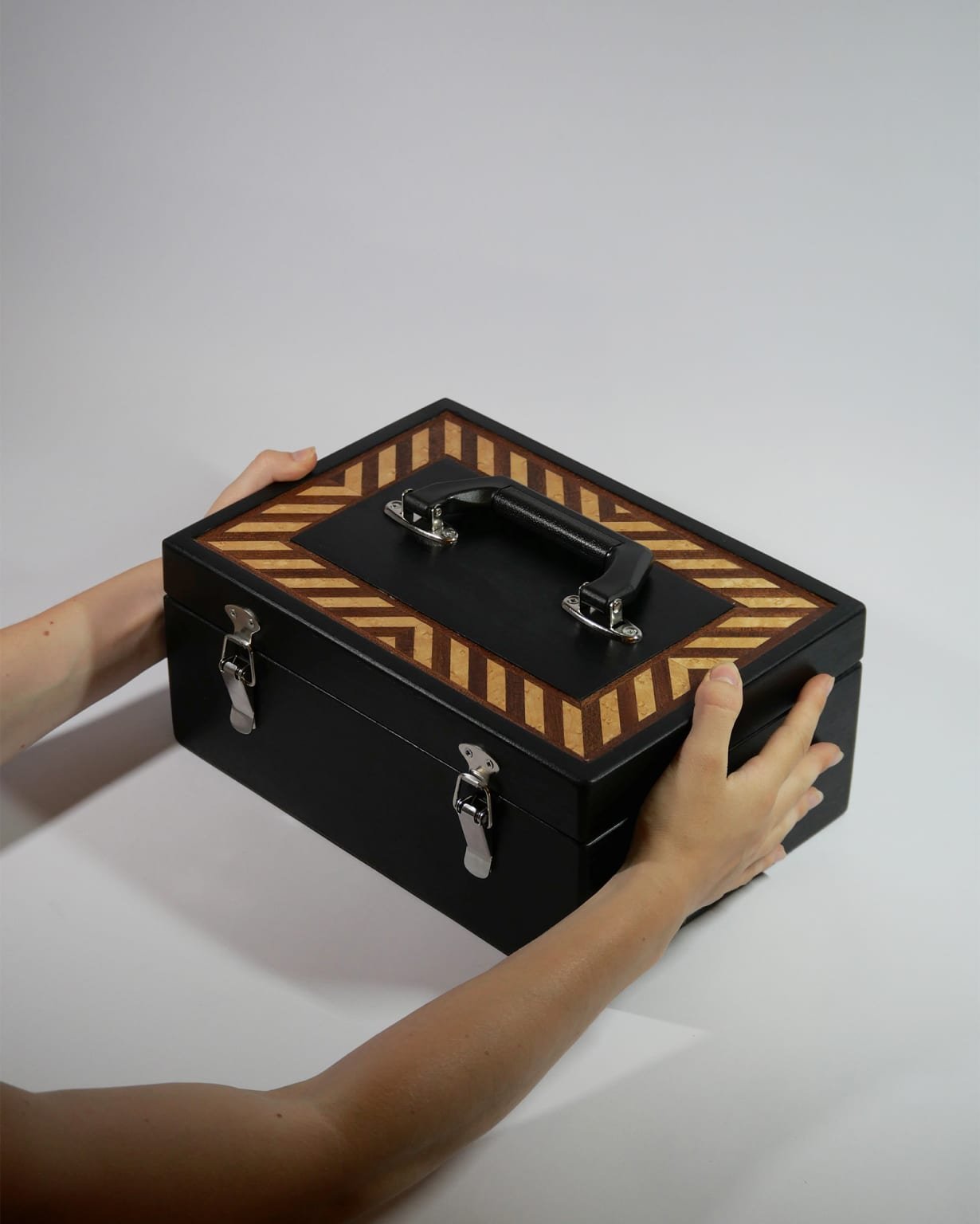 Le coffret fermé, posé sur une table, une main sur son couvercle