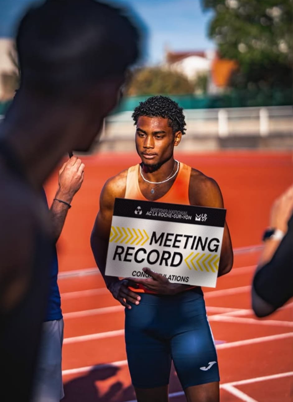 Un athlète tient la pancarte « Meeting record » sur la piste